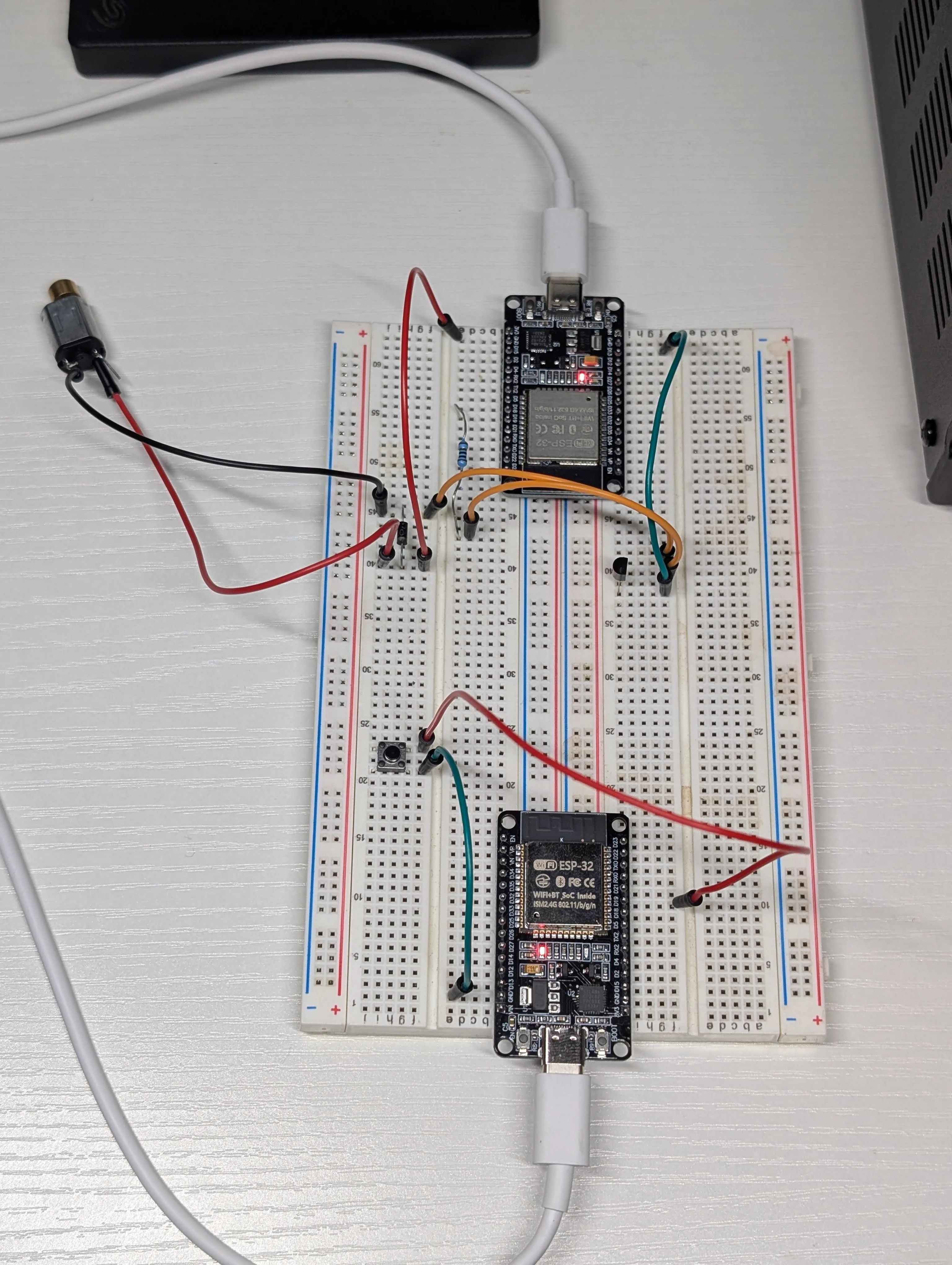 Two-node ESP32 prototype layout with transmitter button and receiver actuator wiring