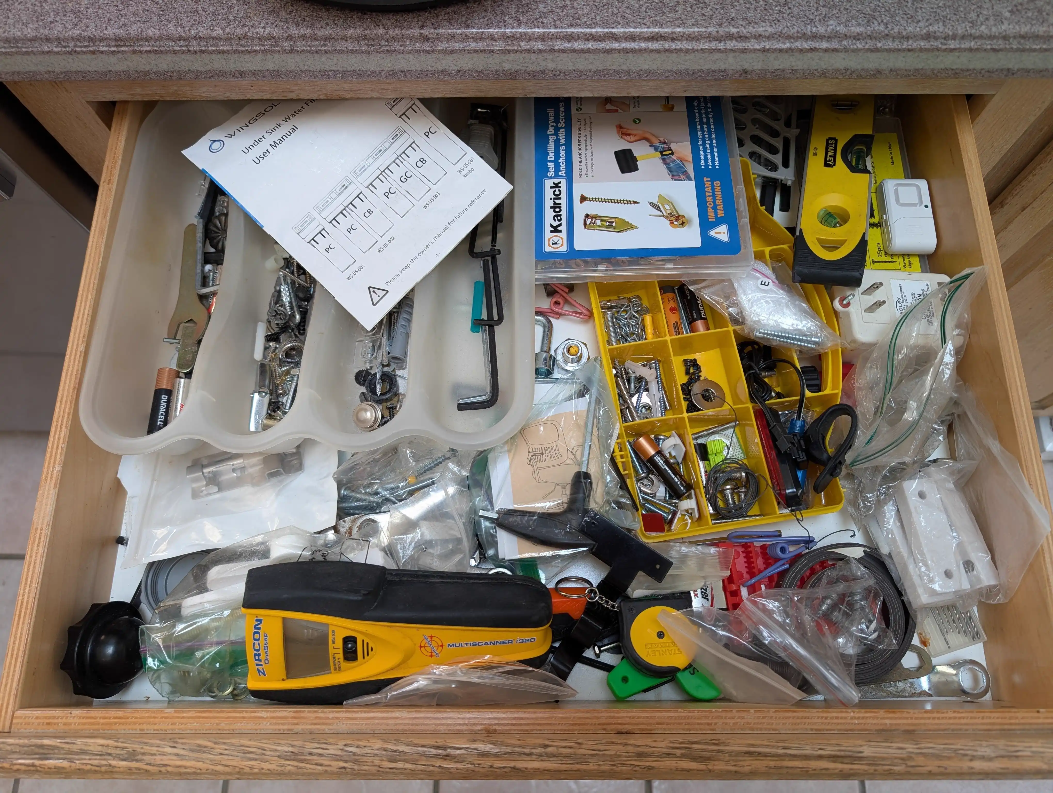 Kitchen junk drawer before organization with mixed tools and hardware