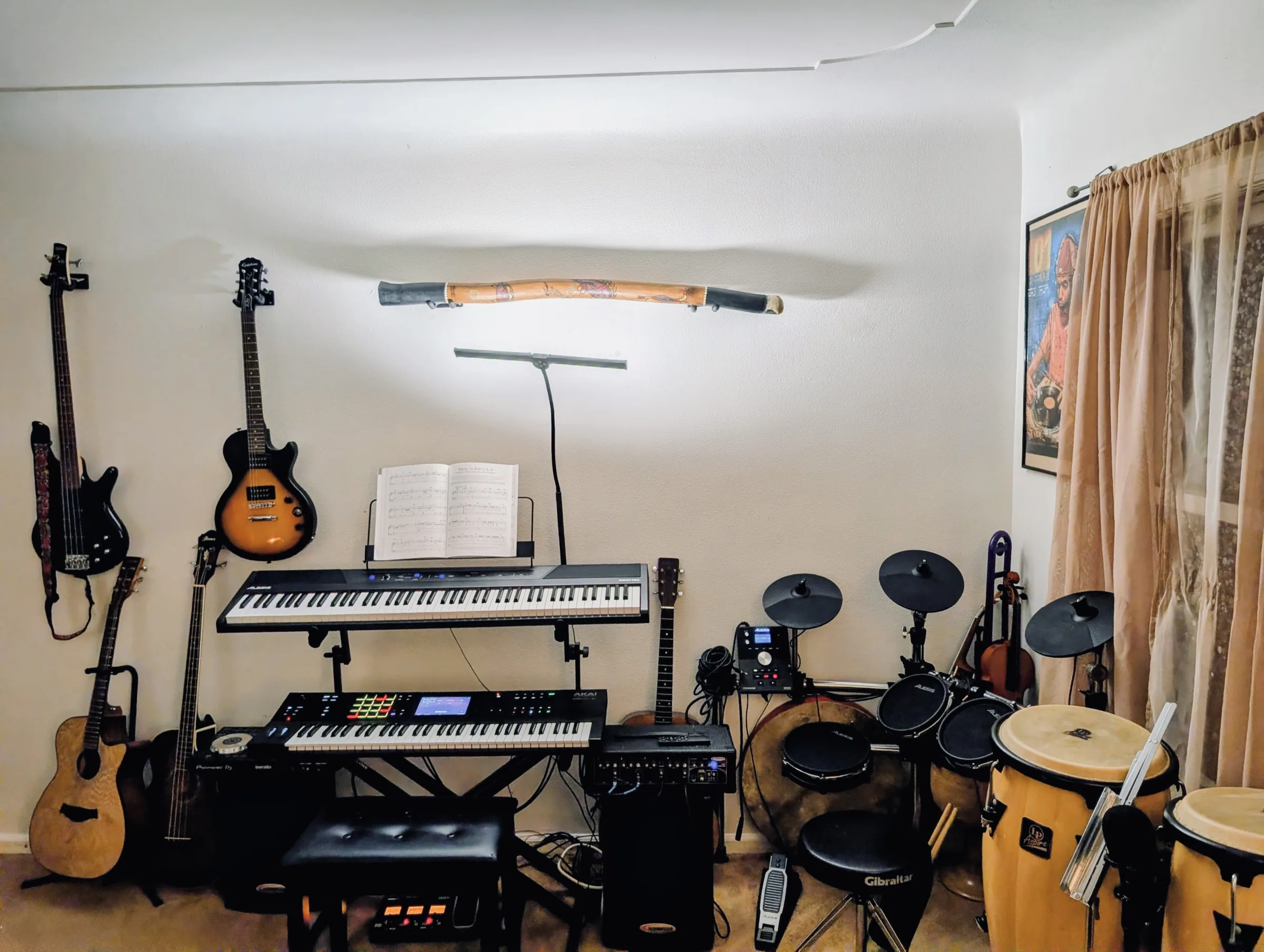 Living room music studio with keyboards, guitars, drums, and production gear