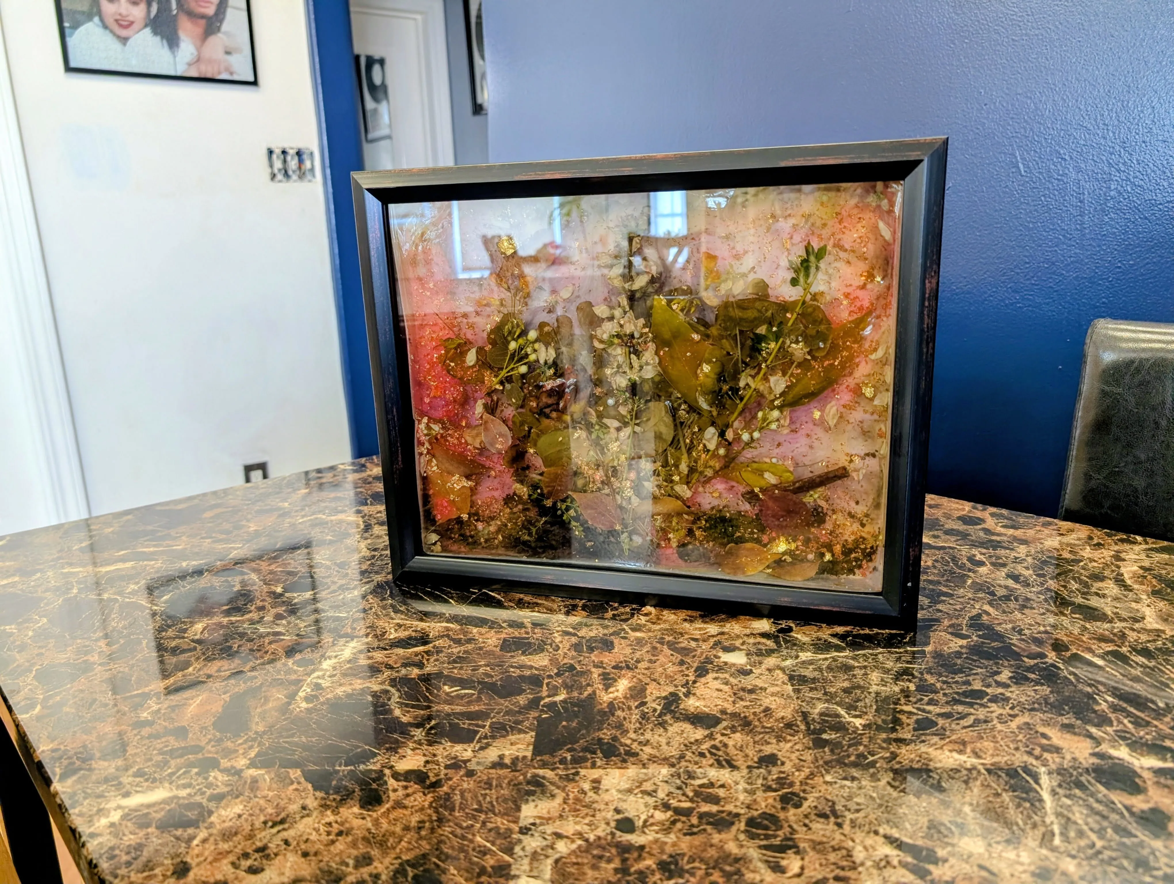 Finished epoxy art piece framed and sitting on a table