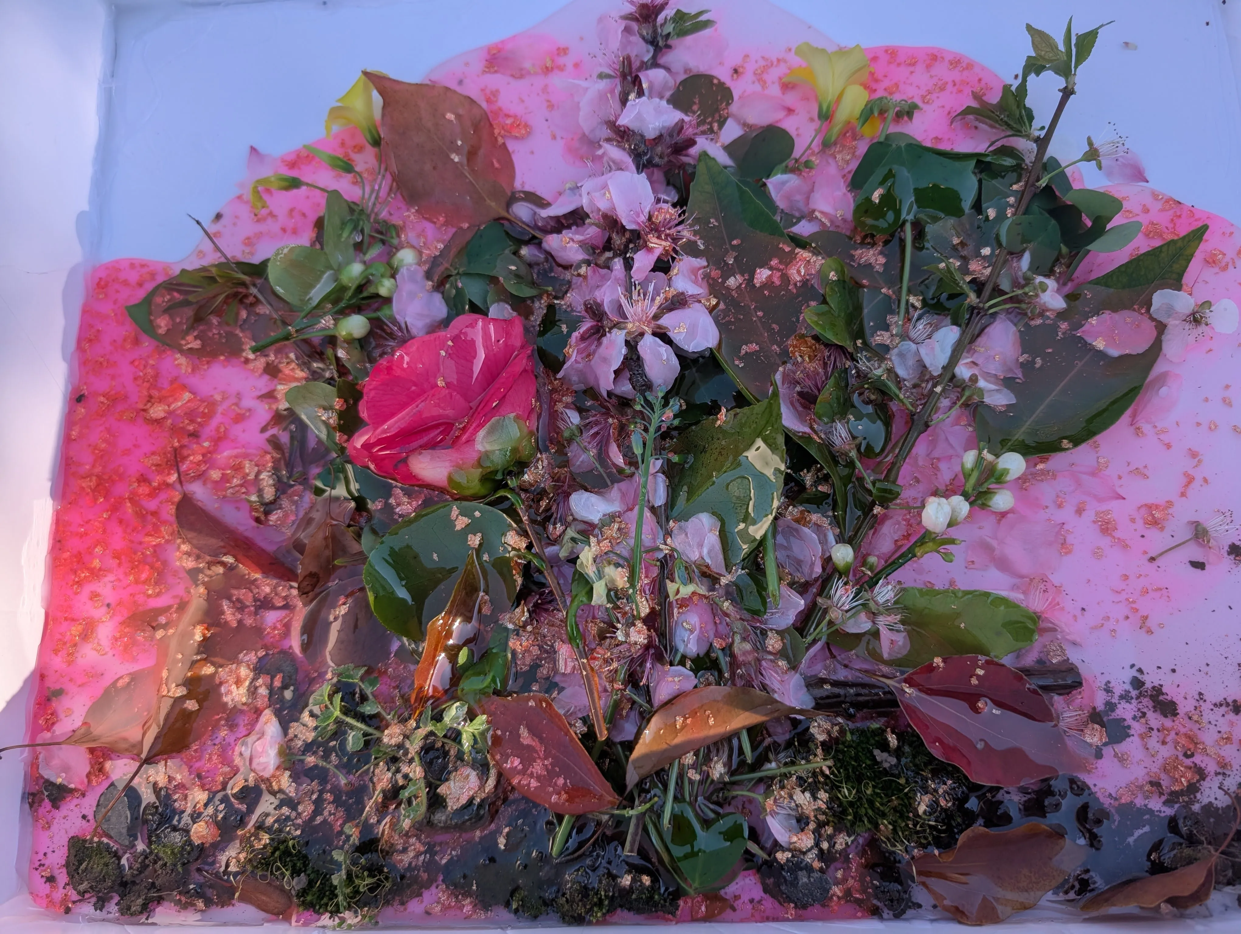 First layer of pink-tinted epoxy with gold flakes poured over the flowers