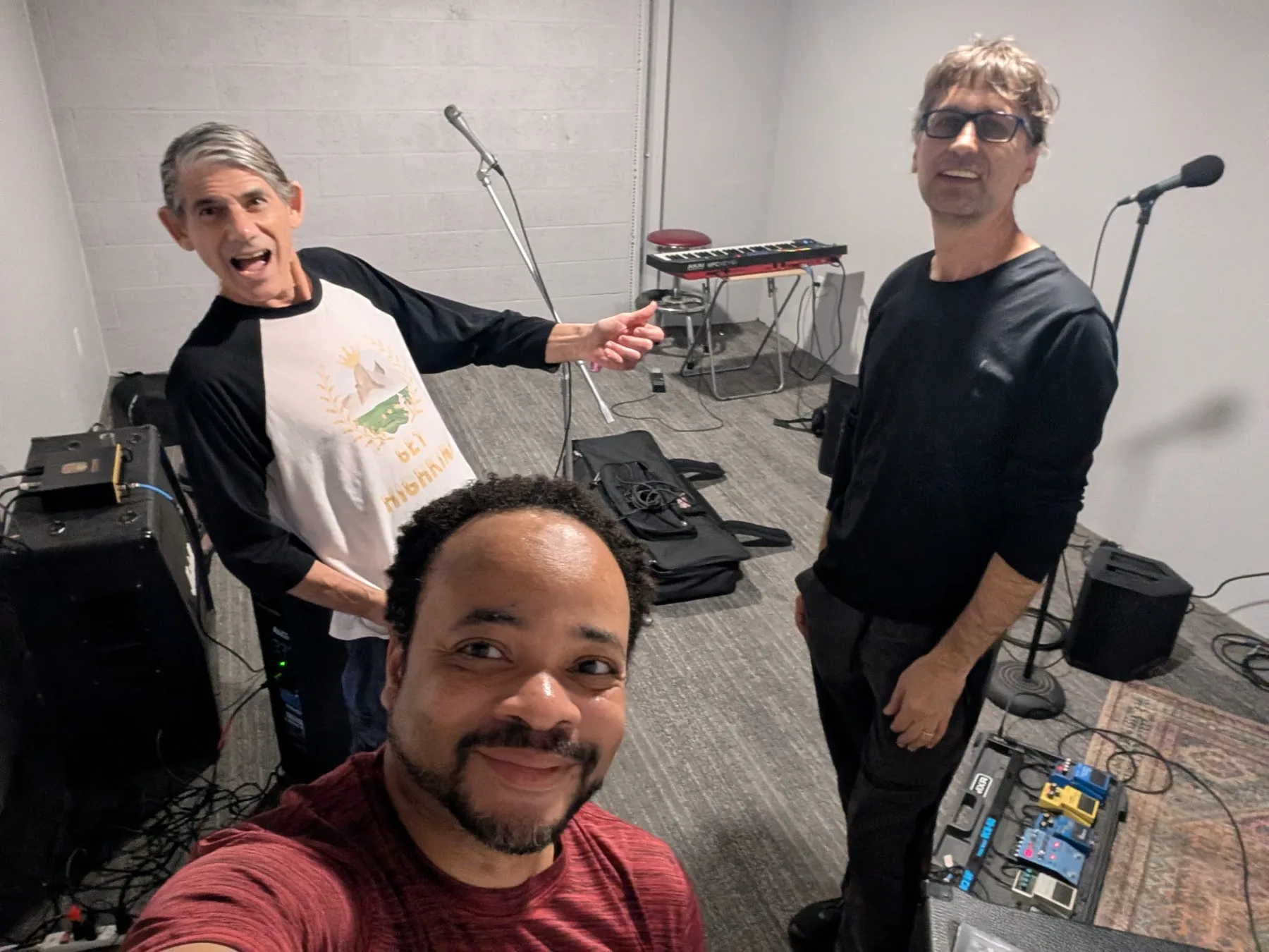 Warren smiling with two bandmates in a rehearsal room