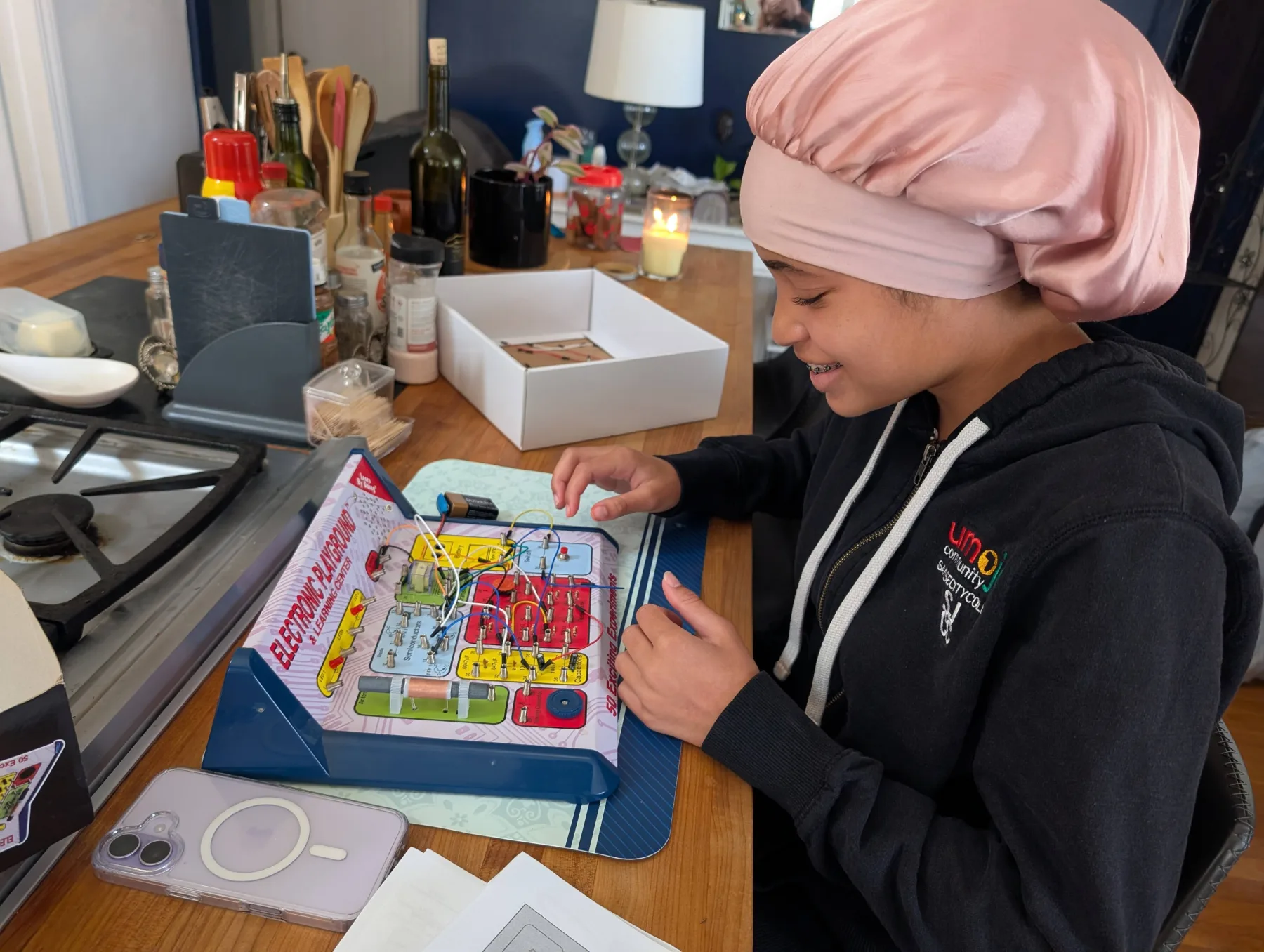 Warren's daughter exploring an electronic circuits learning kit at the kitchen table