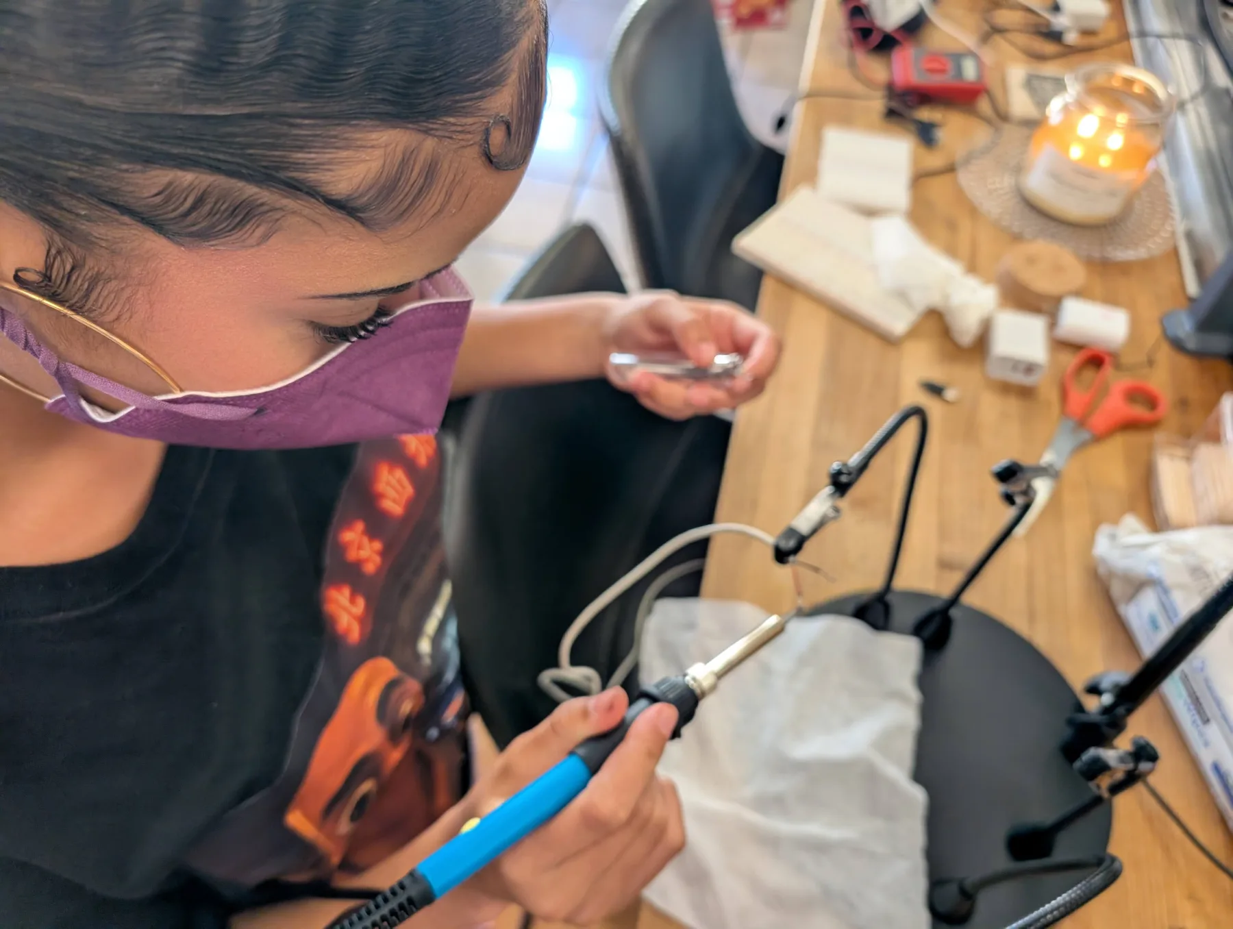 Warren's daughter carefully soldering electronics at a workbench
